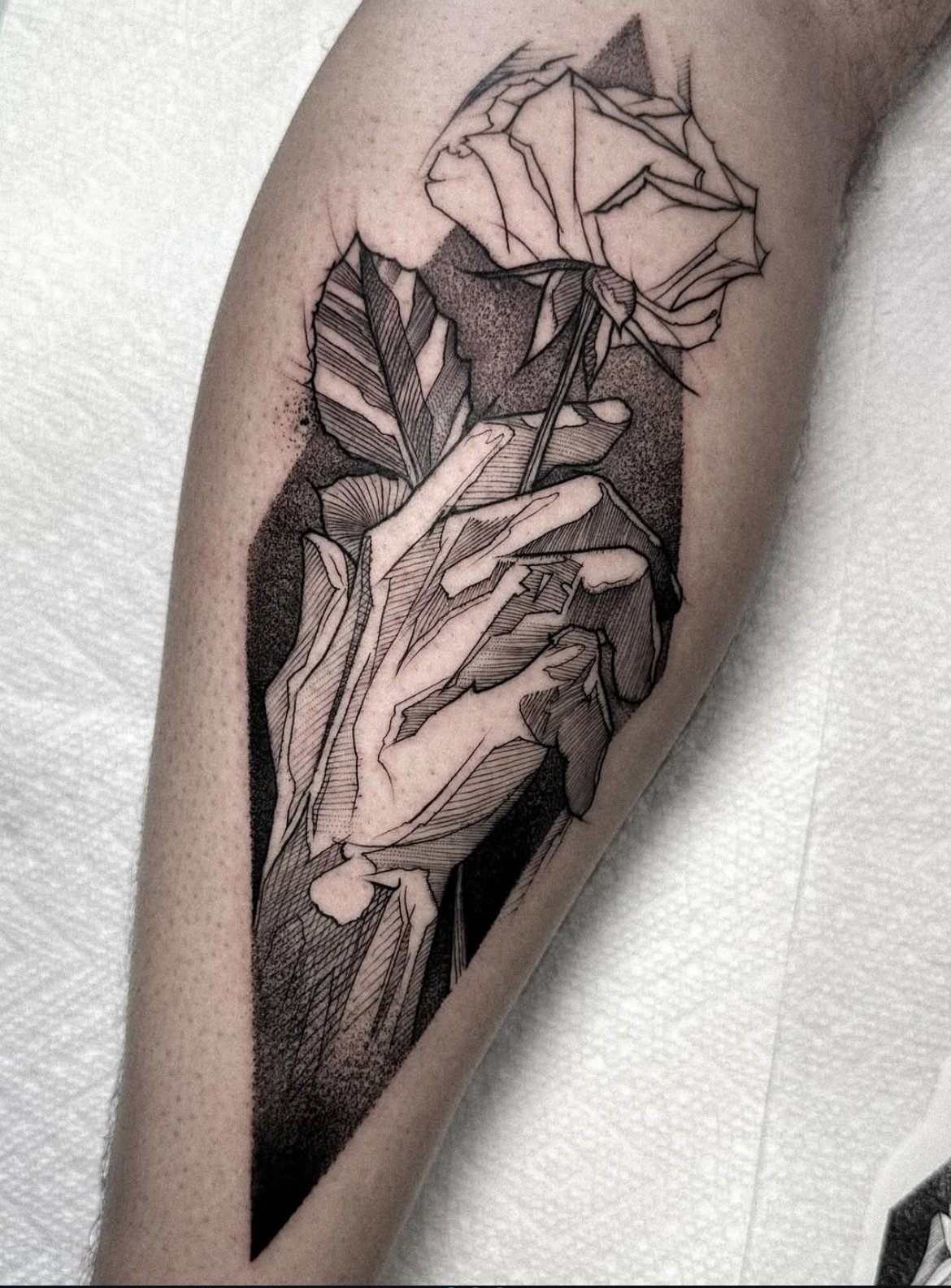 Arsen’s illustrative blackwork tattoo of a hand holding a rose